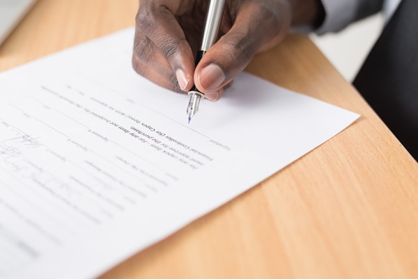 person writing on white paperby Cytonn Photography